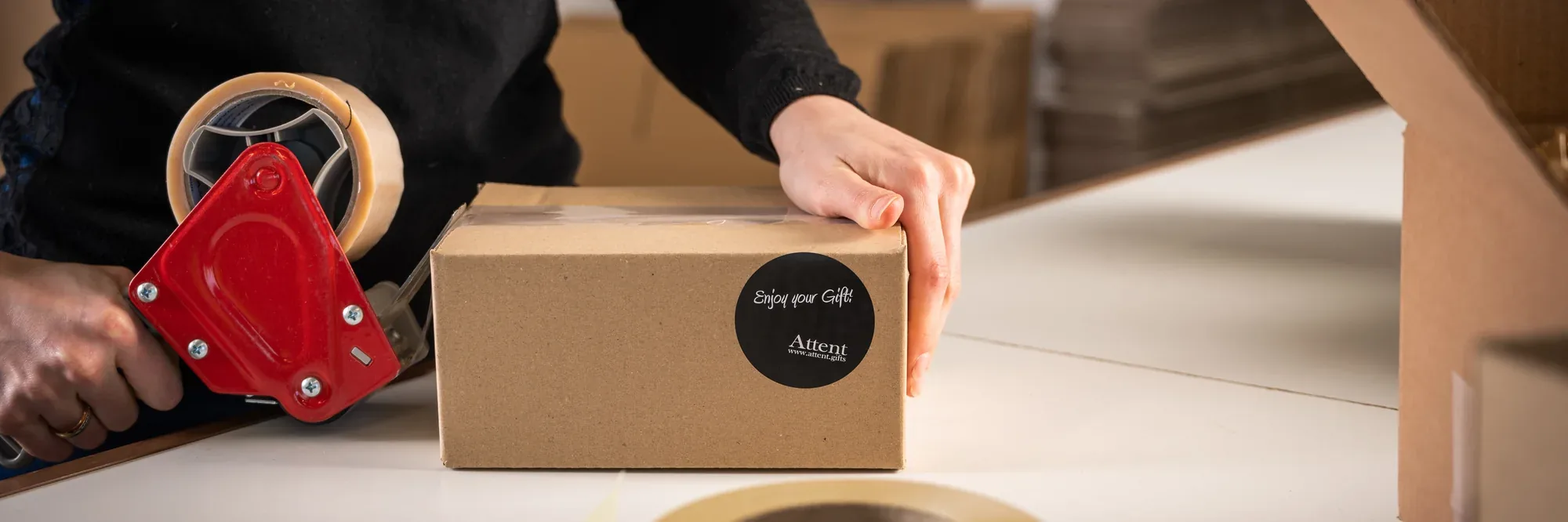 Iemand plakt een geschenkdoos dicht met Attent-tape