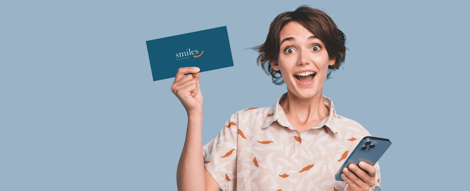 Vrouw met smartphone houdt een Smiles-geschenkkaart omhoog
