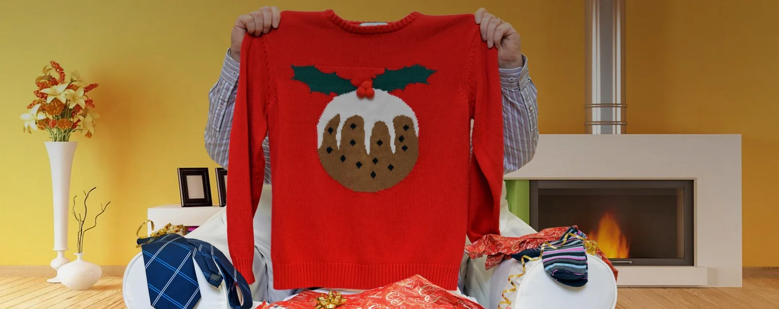 Iemand houdt een rode kersttrui omhoog bij de haard